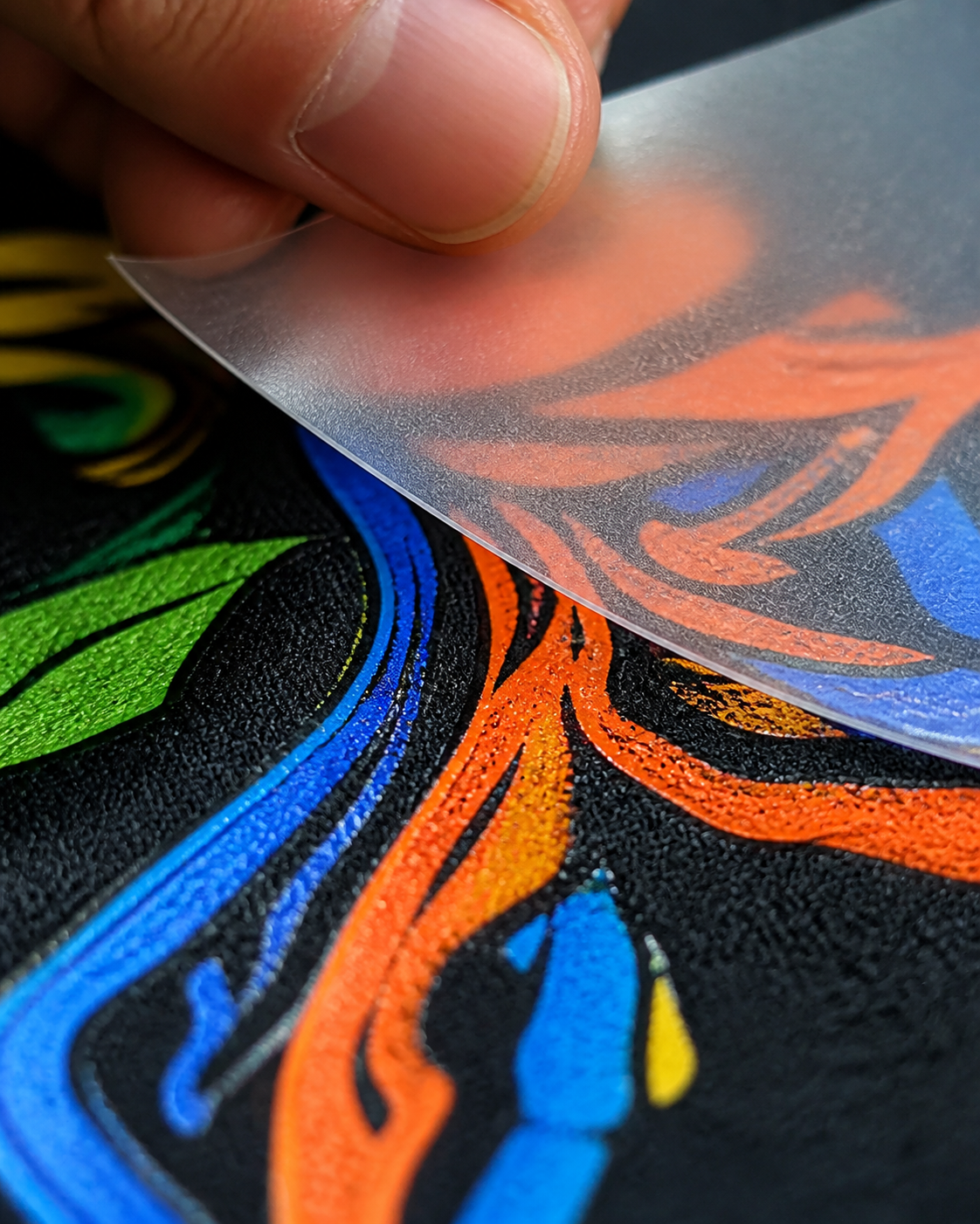 A full-color DTF transfer being peeled from fabric